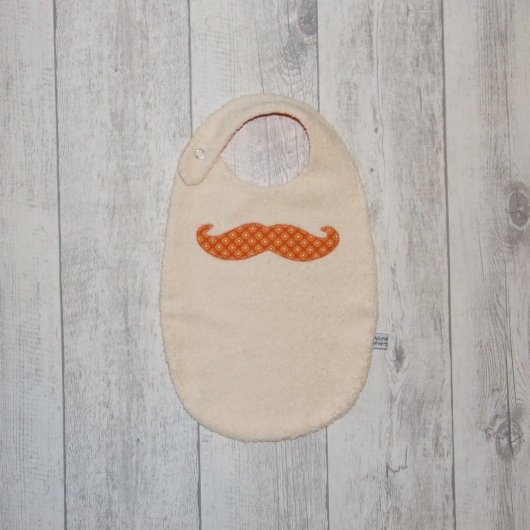 Bavoir moustache imprimé pois jaune sur fond orange